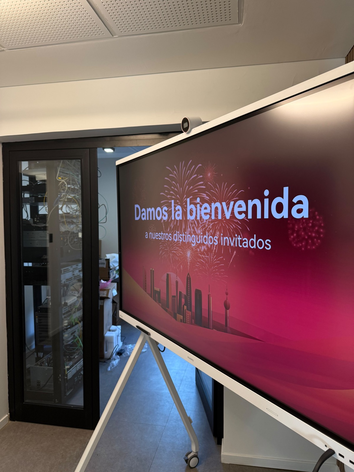 Pantalla Huawei IdeaHub del laboratorio, junto al rack de equipamiento.